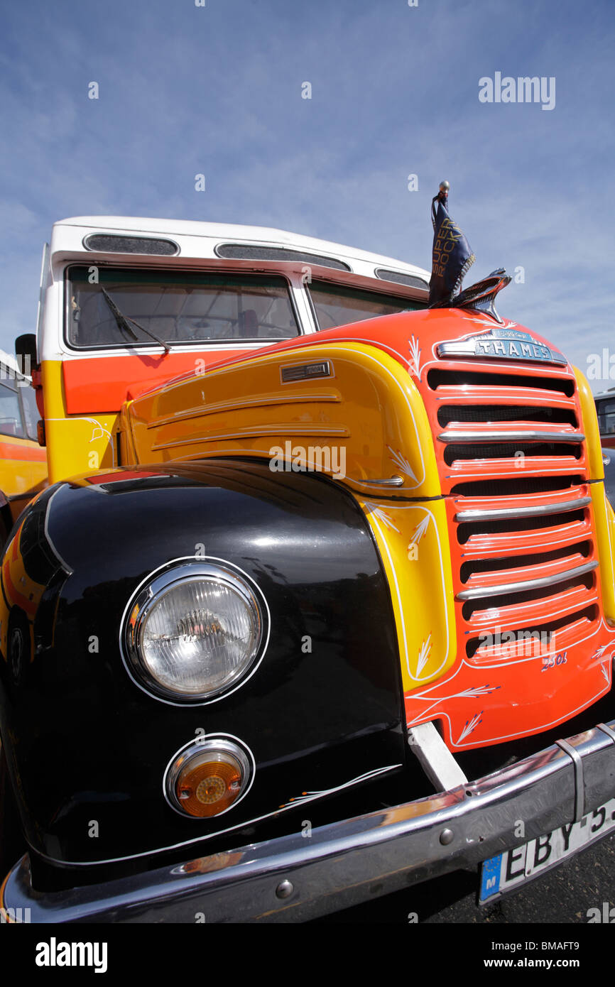 An old fashioned 'bull-nose' bus brightly painted yellow orange white ...
