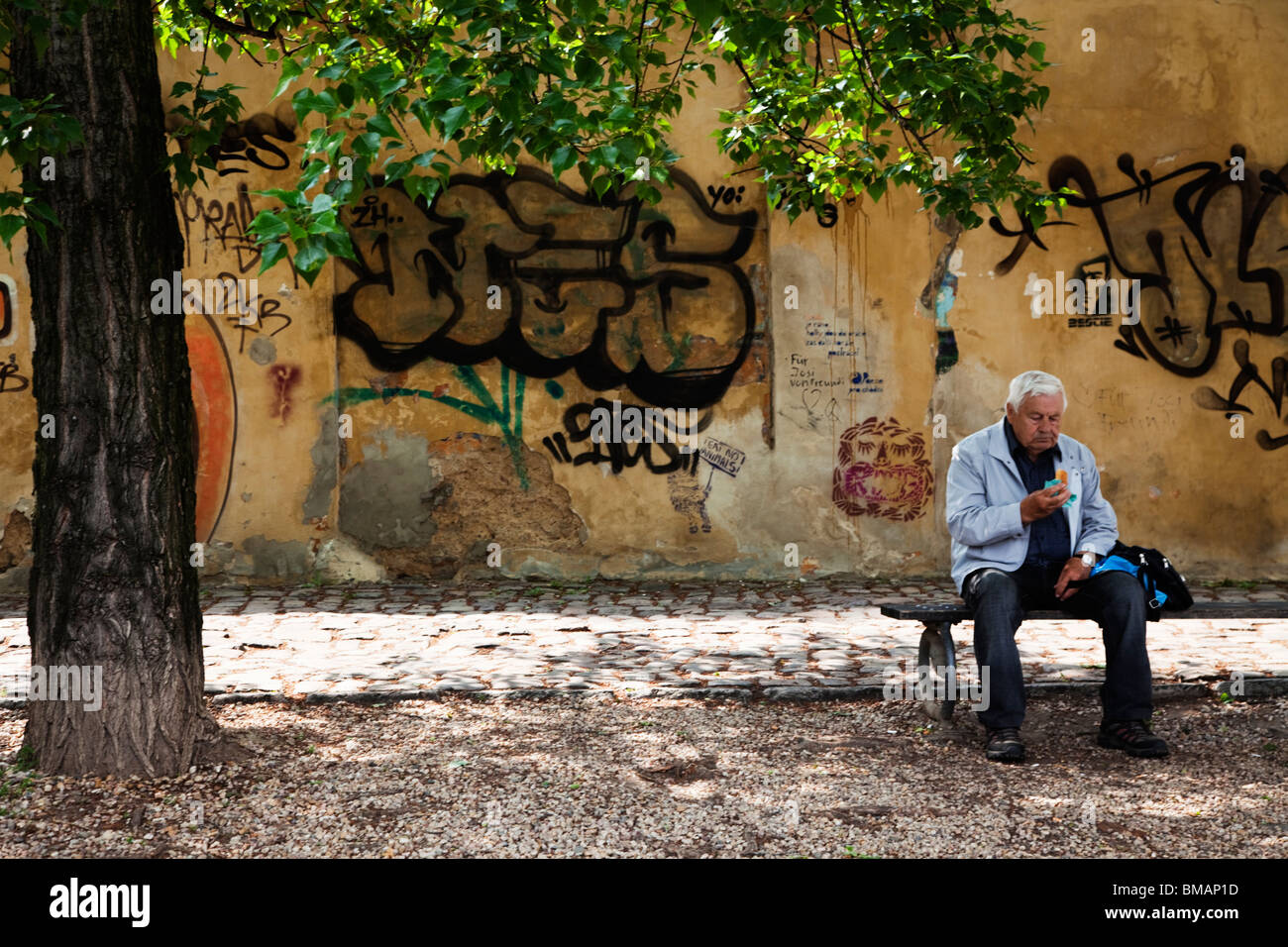 Old man is eating a sandwich at Kampa Island in Prague Stock Photo