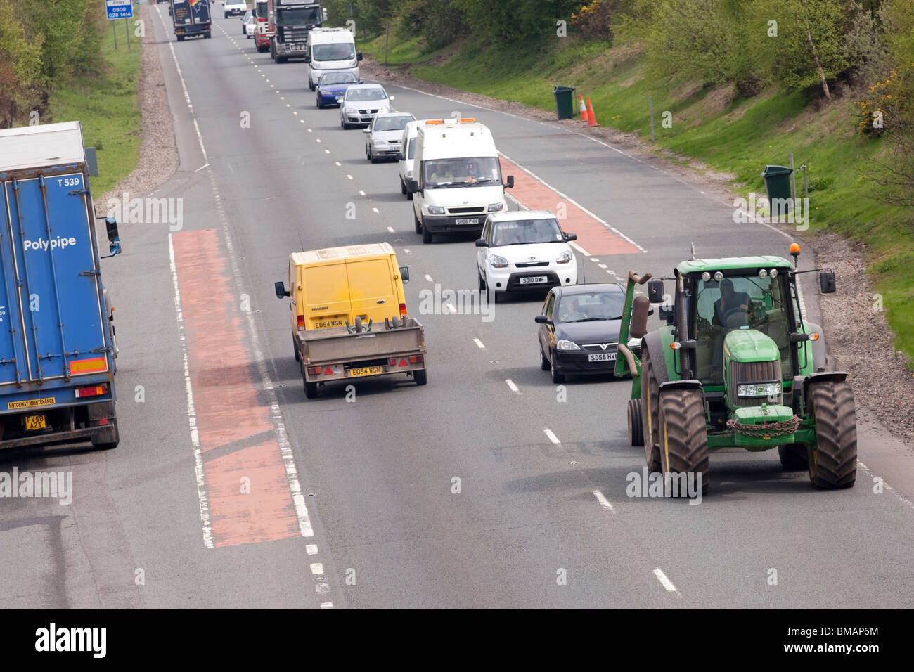 A queue of traffic behind a slow moving vehicle tractor on the A75 road near Dumfries Dumfries and Galloway Scotland UK Stock Photo