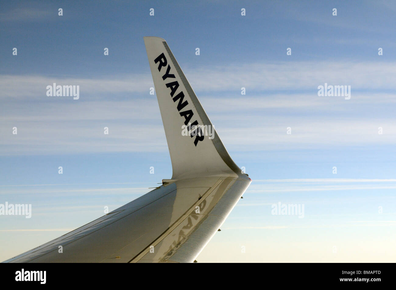 Aircraft winglet carrying the name Ryanair a low cost European airline and open skies backdrop seen from the cabin of a Boeing Stock Photo
