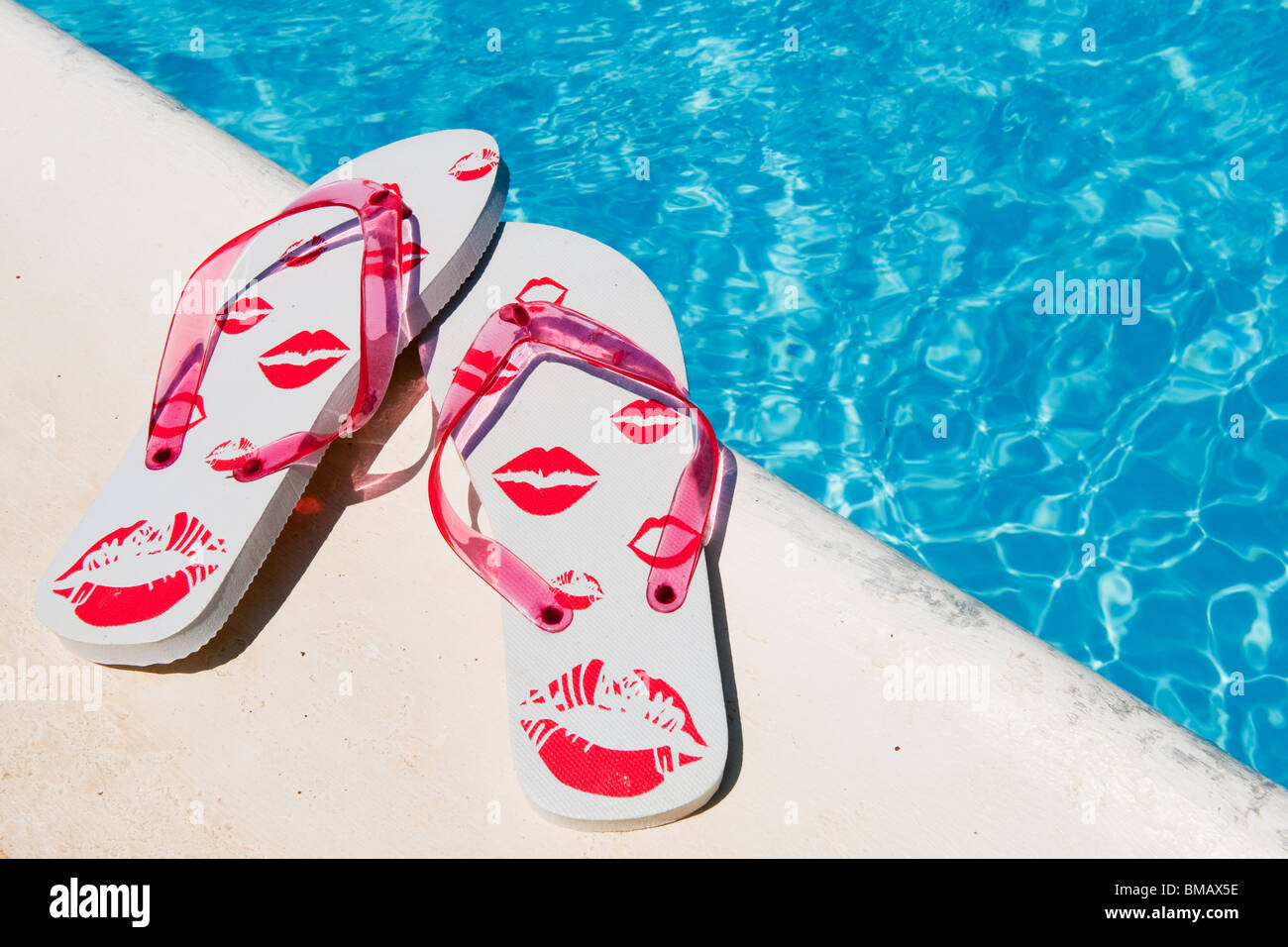 Flip flops near the swimming pool with blue water Stock Photo - Alamy