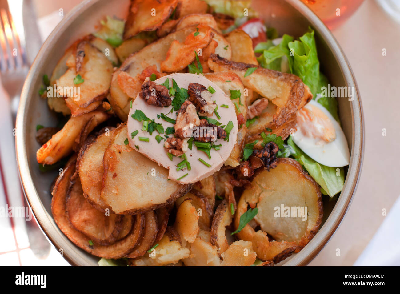 A salad is topped with fried potatoes, sliced hard-boiled egg, and foie gras at a restaurant in Paris Stock Photo