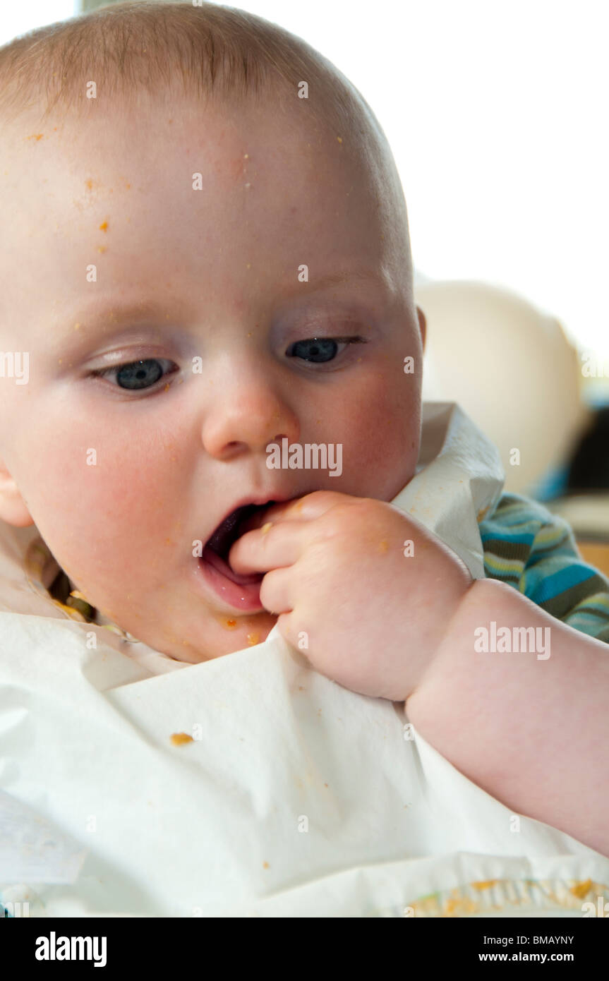 Baby putting food in his mouth Stock Photo Alamy
