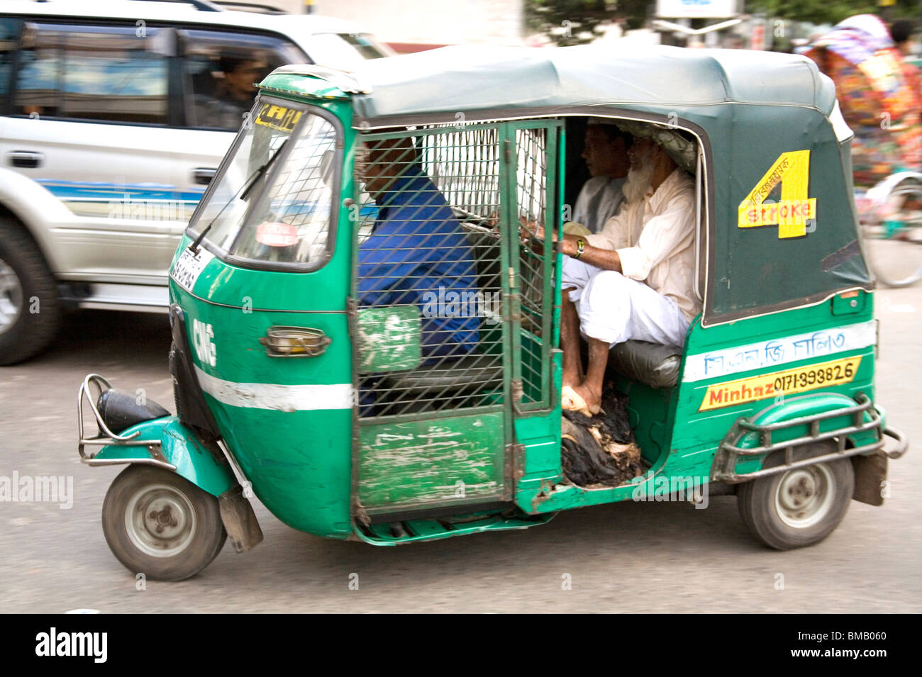 Street scene ; passengers sitting in green color auto rickshaw ; Dhaka