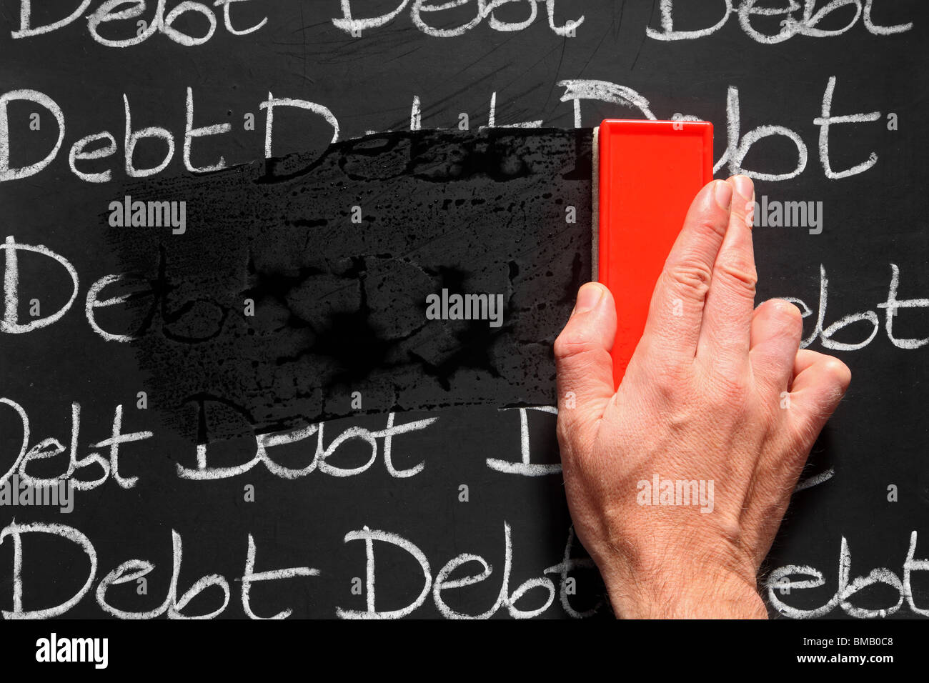 Wiping debts away on a blackboard with a red chalk duster. Stock Photo