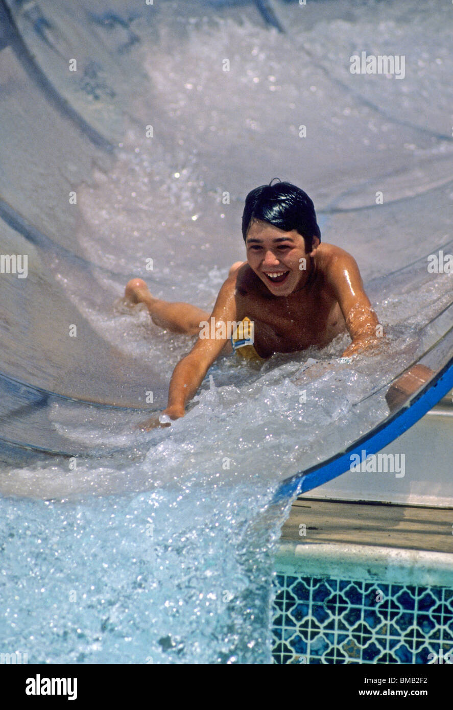 Boy swim water slide fun laugh thrill sport recreation wet pool tube happy  kid speedo swim suit tan sun Stock Photo - Alamy