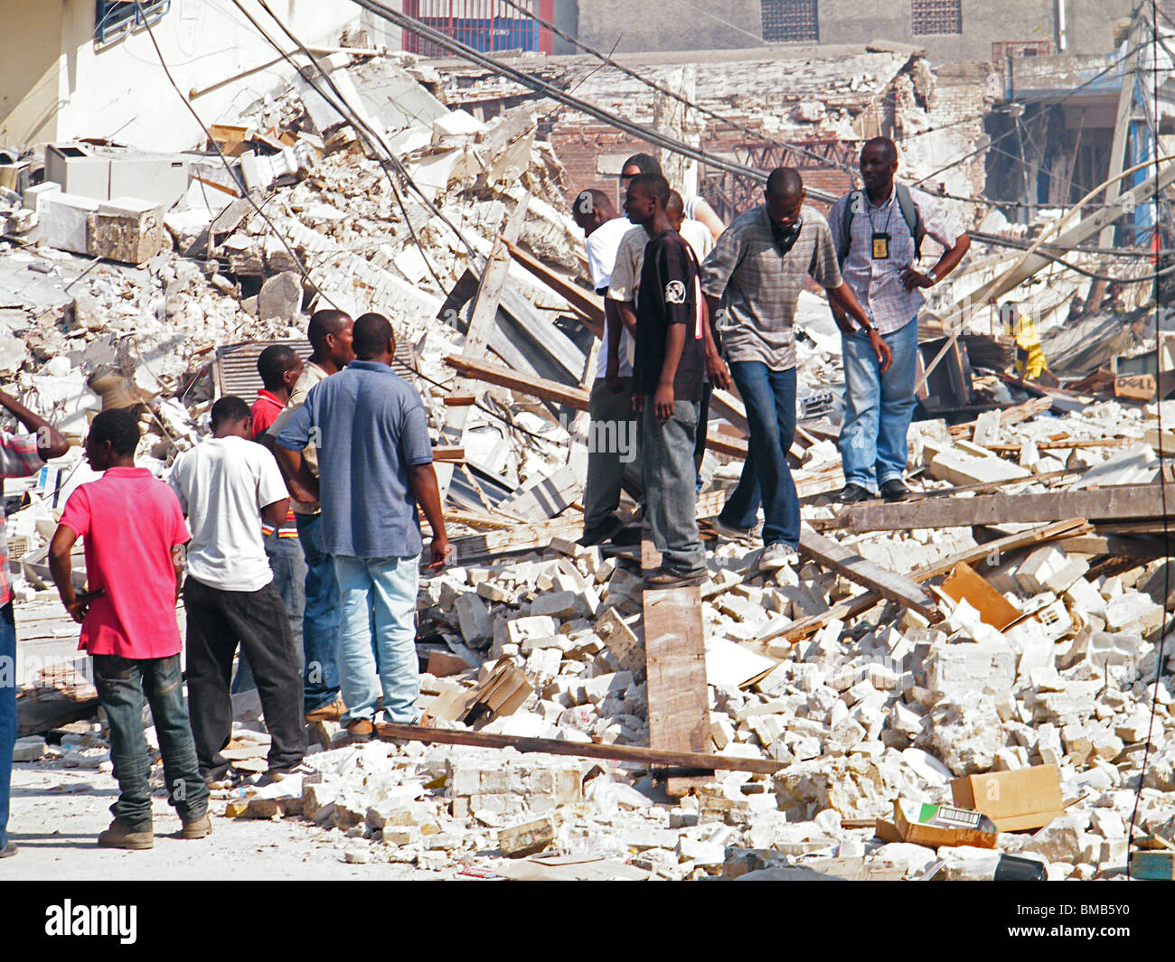 Haitians walk over rubble amid the total devastation of central Port au Prince after the Haiti earthquake Stock Photo