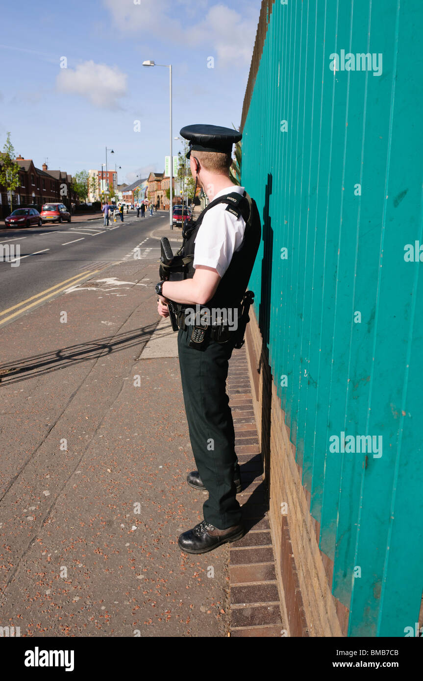 Armed police officer with a Heckler and Koch G36C assault rifle, standing on the Falls Road, policing a 'White Line Picket' Stock Photo