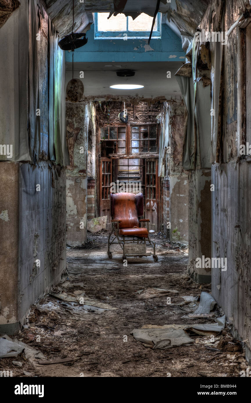 Dilapidated Hospital Chair in a Derelict Psychiatric Asylum Stock Photo