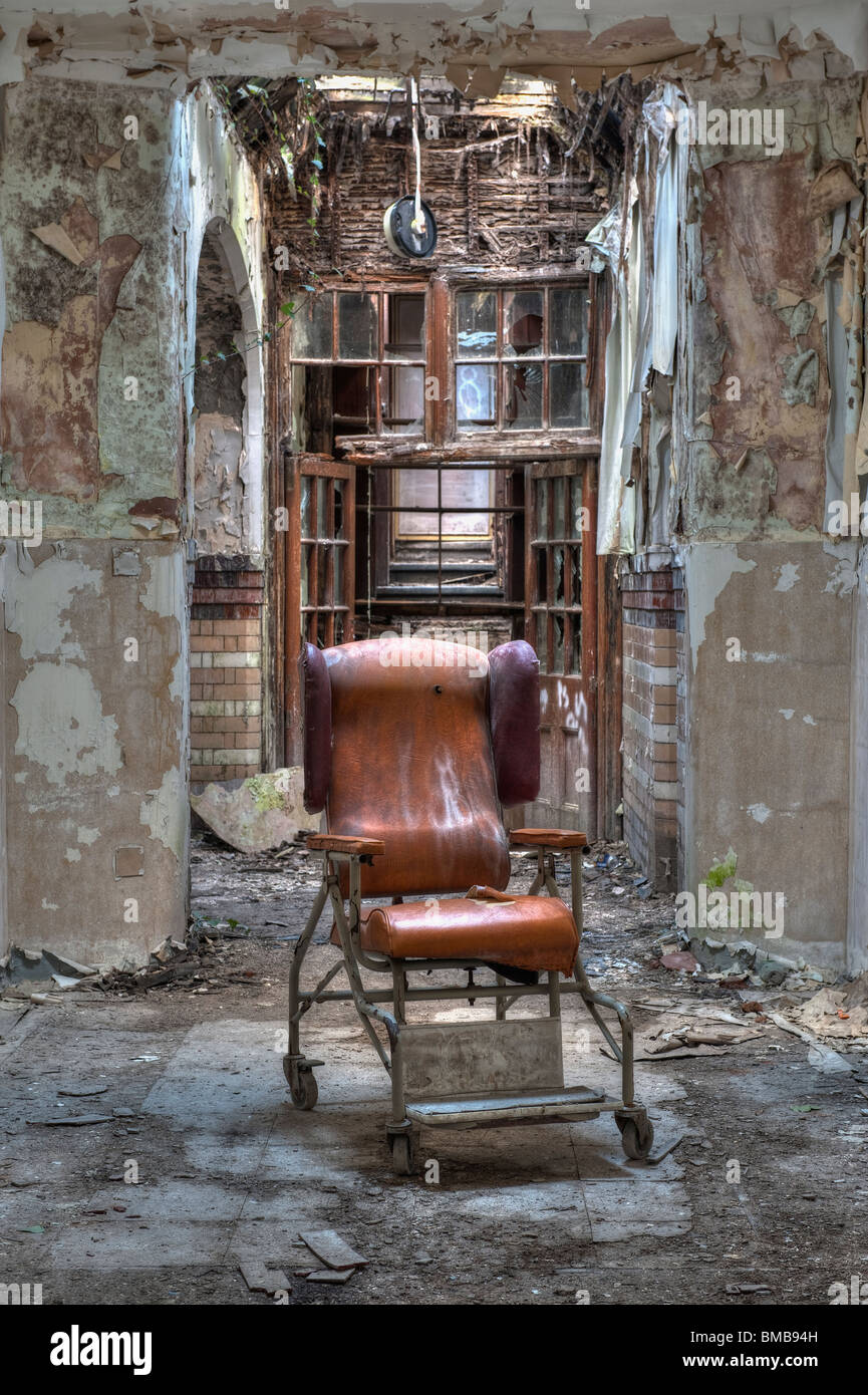 Dilapidated Hospital Chair in a Derelict Psychiatric Asylum Stock Photo