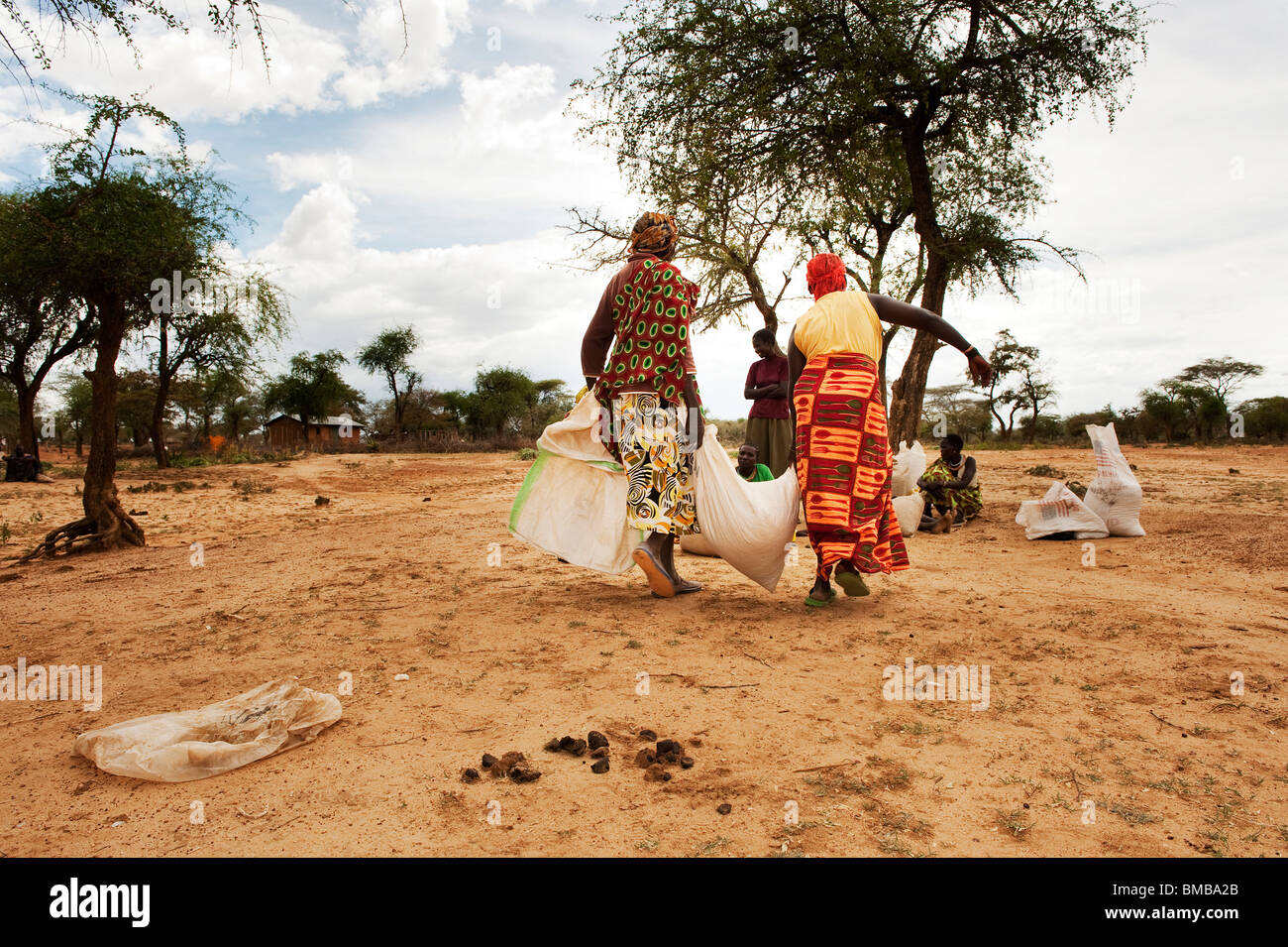 Two women are carrying away their ration of food that they got at the ...