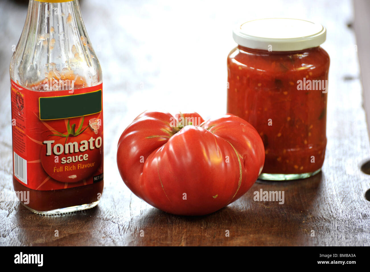 A generic supermarket tomato sauce alongside a home-made version with a beefsteak tomato. Stock Photo