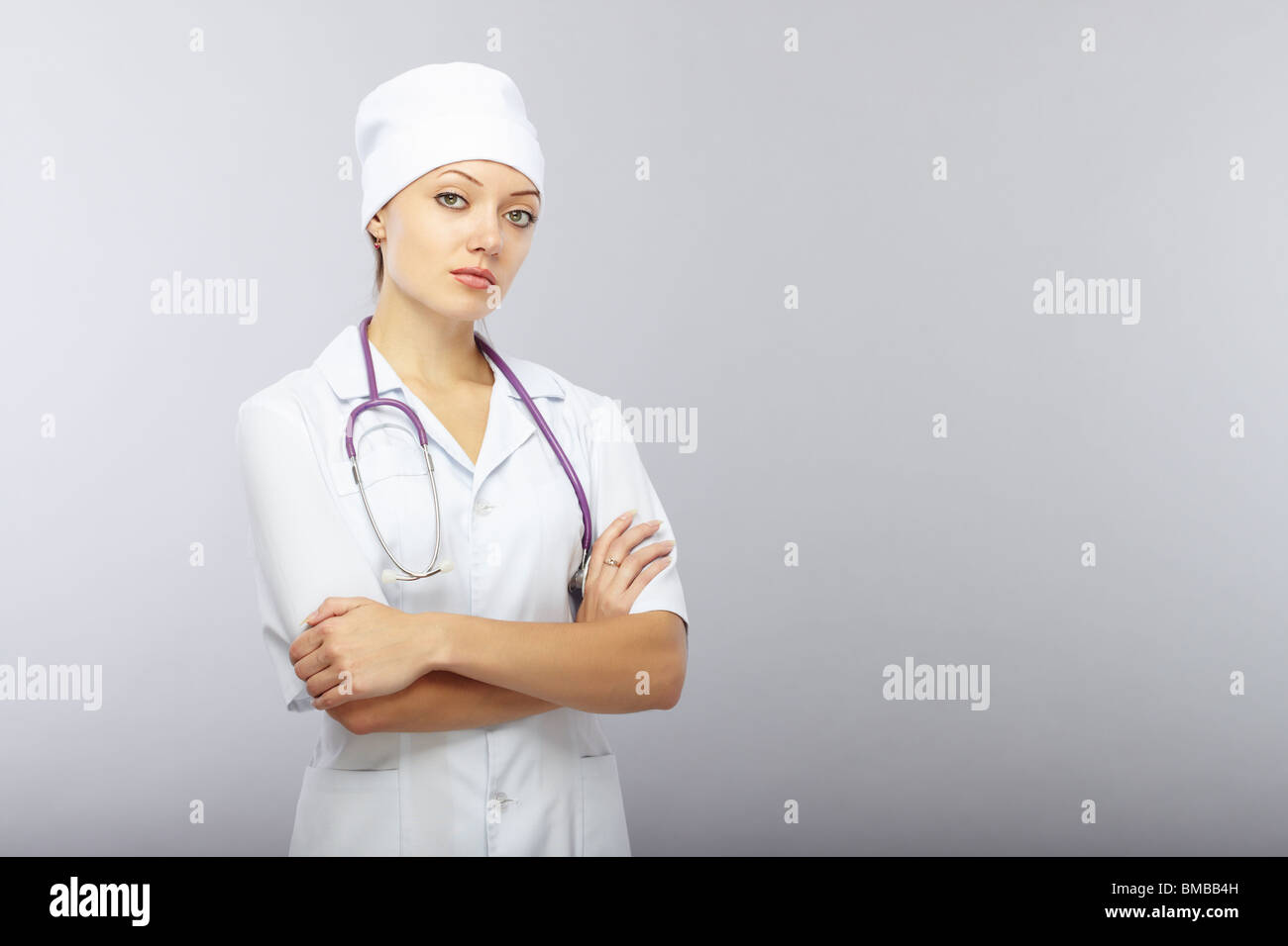 Cross-armed doctor with stethoscope on a gray background. Healthcare theme Stock Photo