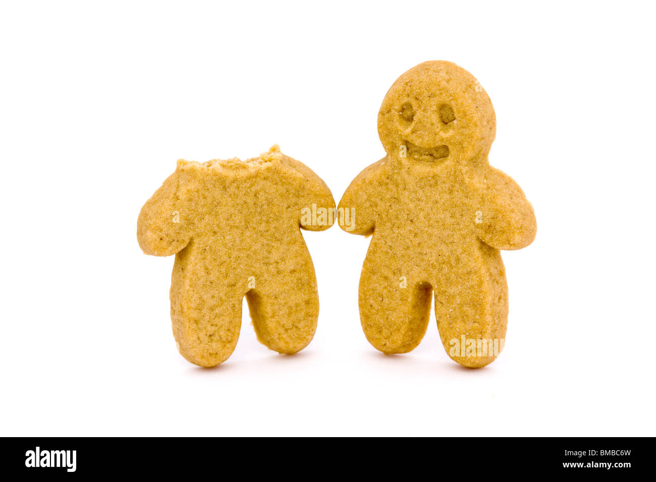 two gingerbread men one with head bitten off on a white background Stock Photo