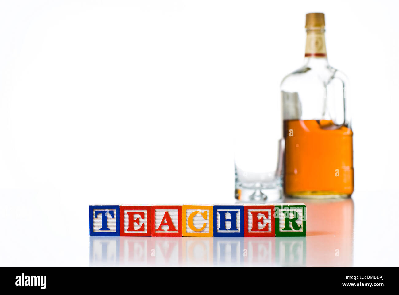 Colorful children's blocks spelling TEACHER with a bottle of liquor and glass Stock Photo