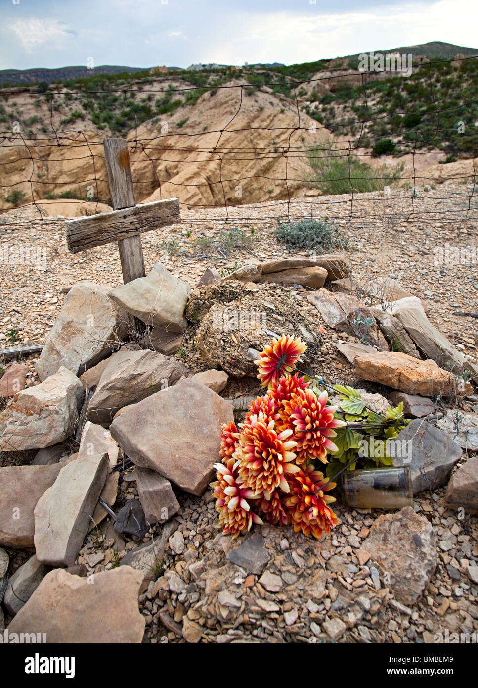 Plastic flowers on old grave of miner with wooden cross Terlingua cemetery Texas USA Stock Photo