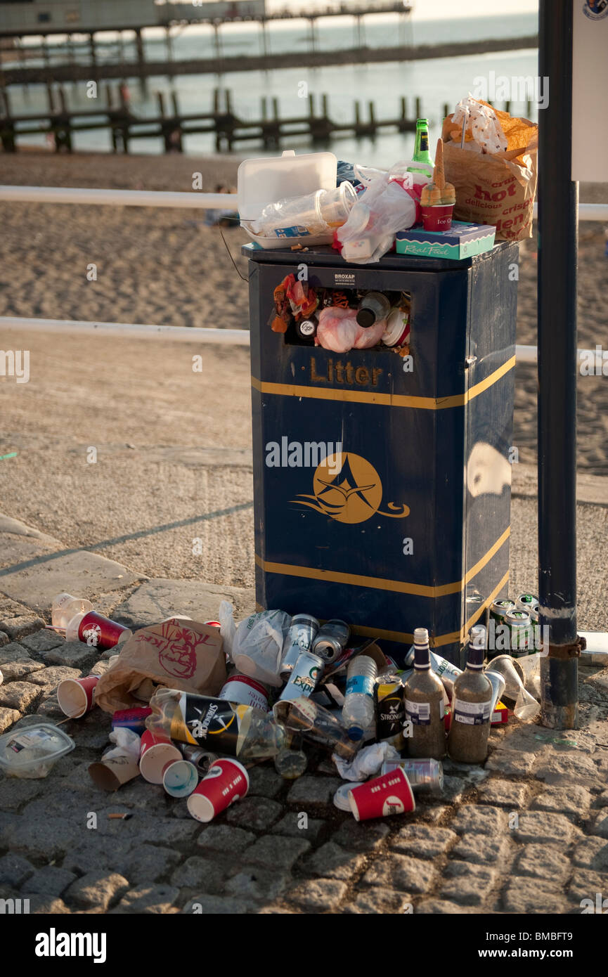 Overflowing rubbish bin at the seaside at the end of a summer day, UK Stock Photo