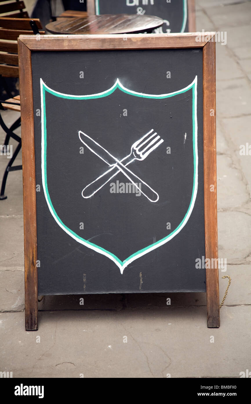 Knife and fork sign on blackboard showing food is available Stock Photo