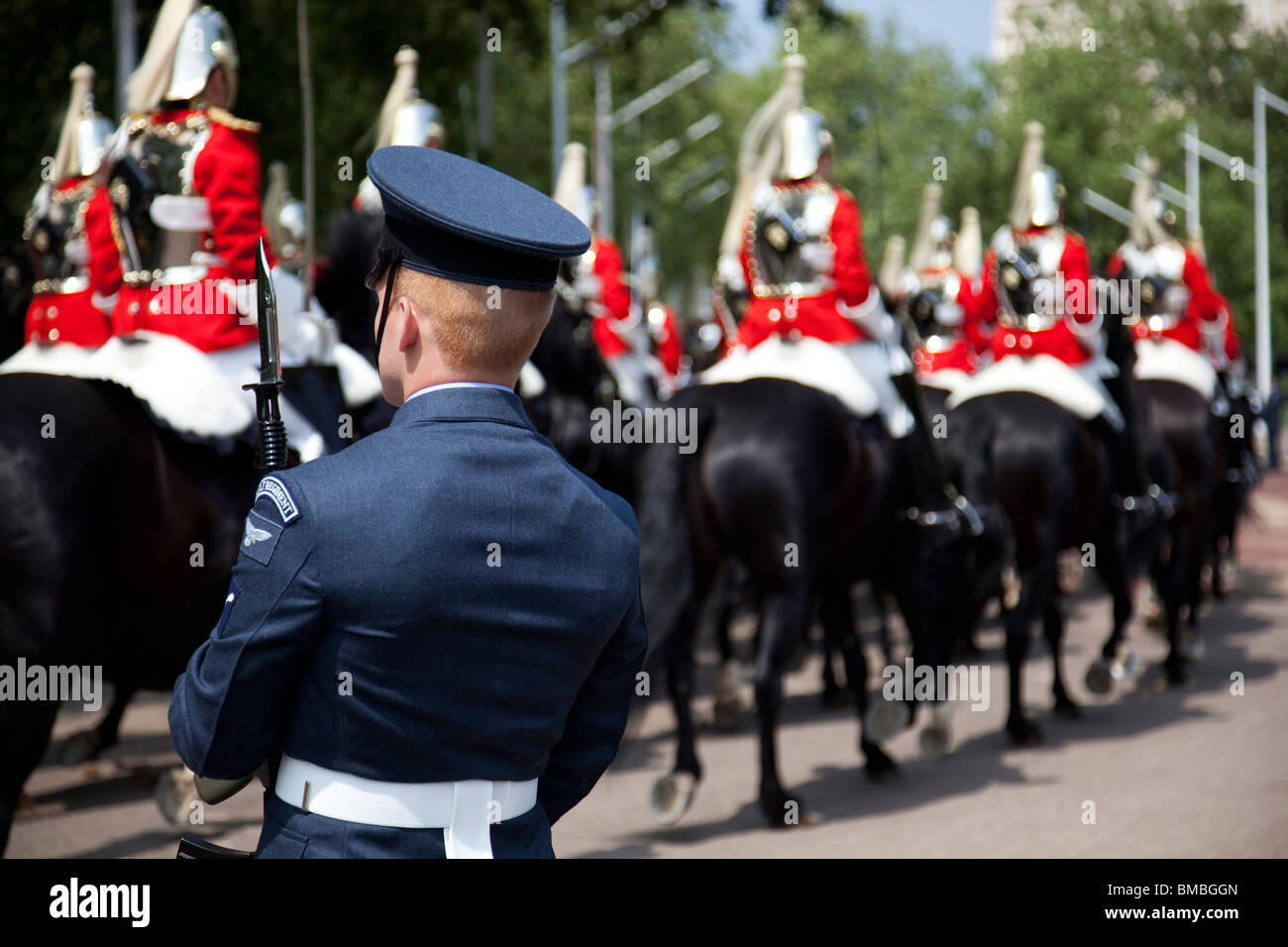 Life Guards pass as a member of the RAF Regiment stands guard. Royal procession for the State Opening of Parliament, London. Stock Photo