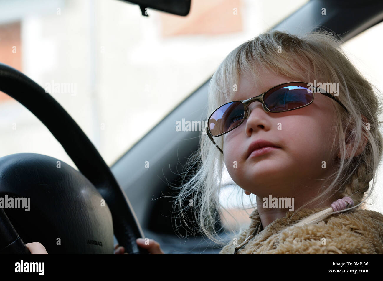 Stock photo of a four year old girl pretending to drive the car Stock