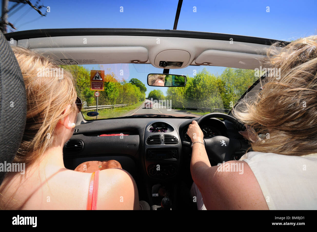 Open top car with female driver and passenger on open road Stock Photo