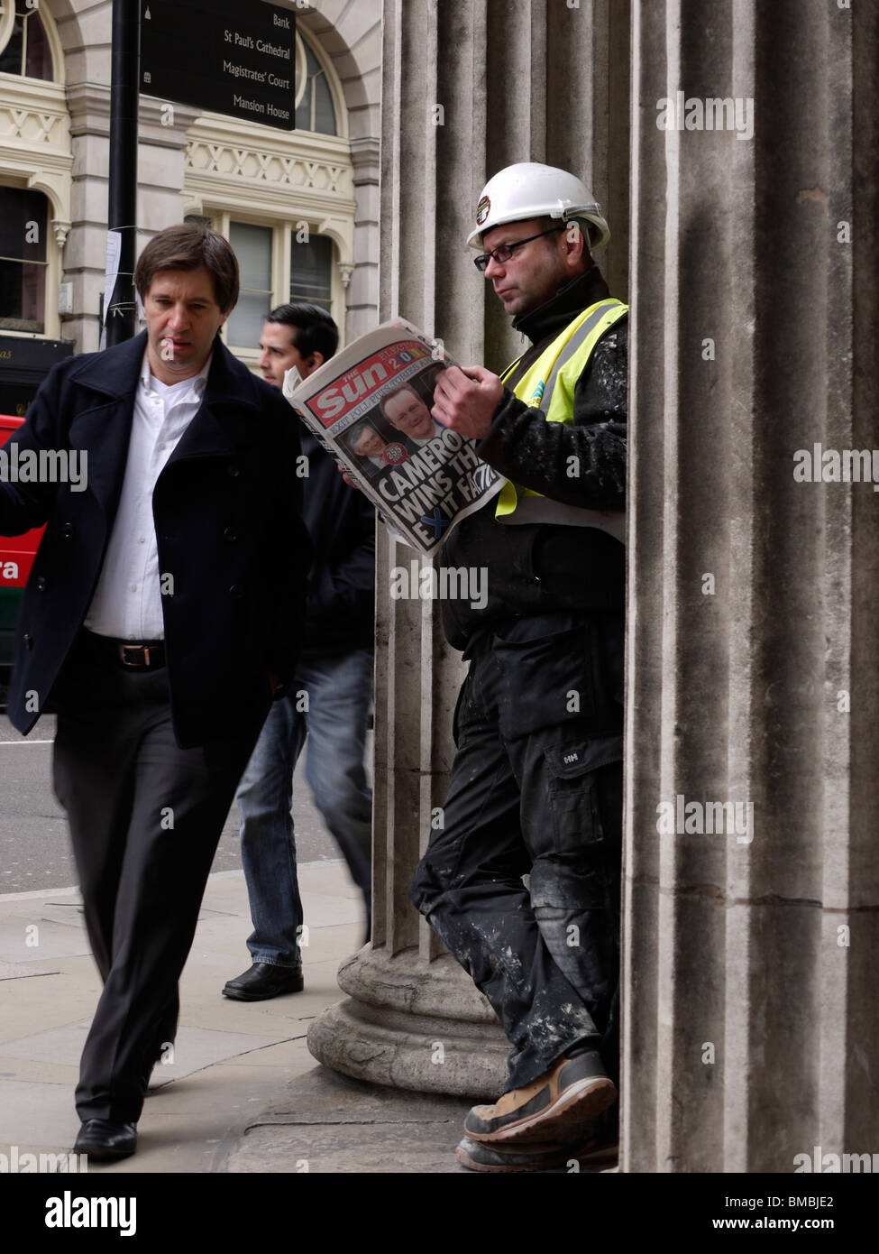 Builder reading The Sun Newspaper outside bank of england, with election headline Cameron wins the exit factor Stock Photo