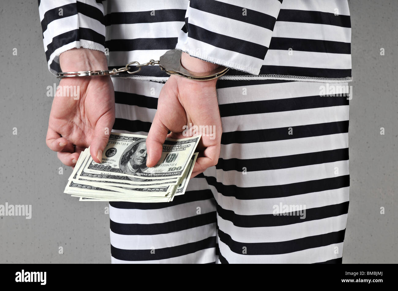 Hands in handcuffs holding pack of 100 dollar bills. Stock Photo