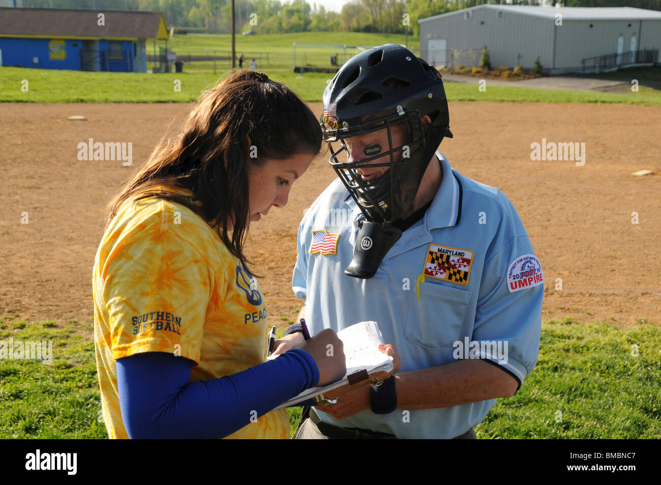 coach discusses a change in the roster with the home plate umpire in a softball game Stock Photo