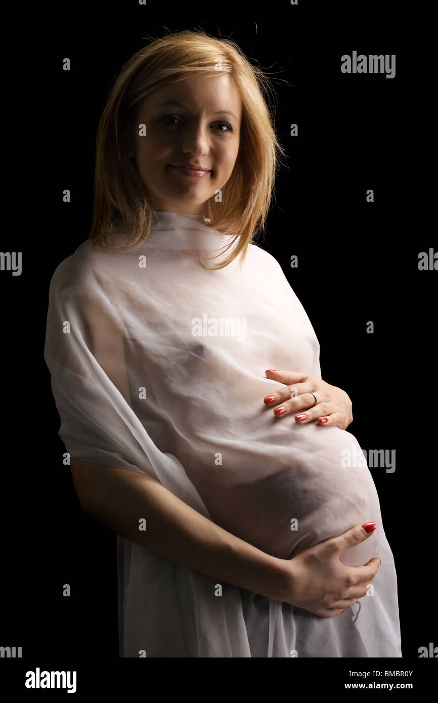 bared pregnant girl in transparent clothes embraces the stomach
