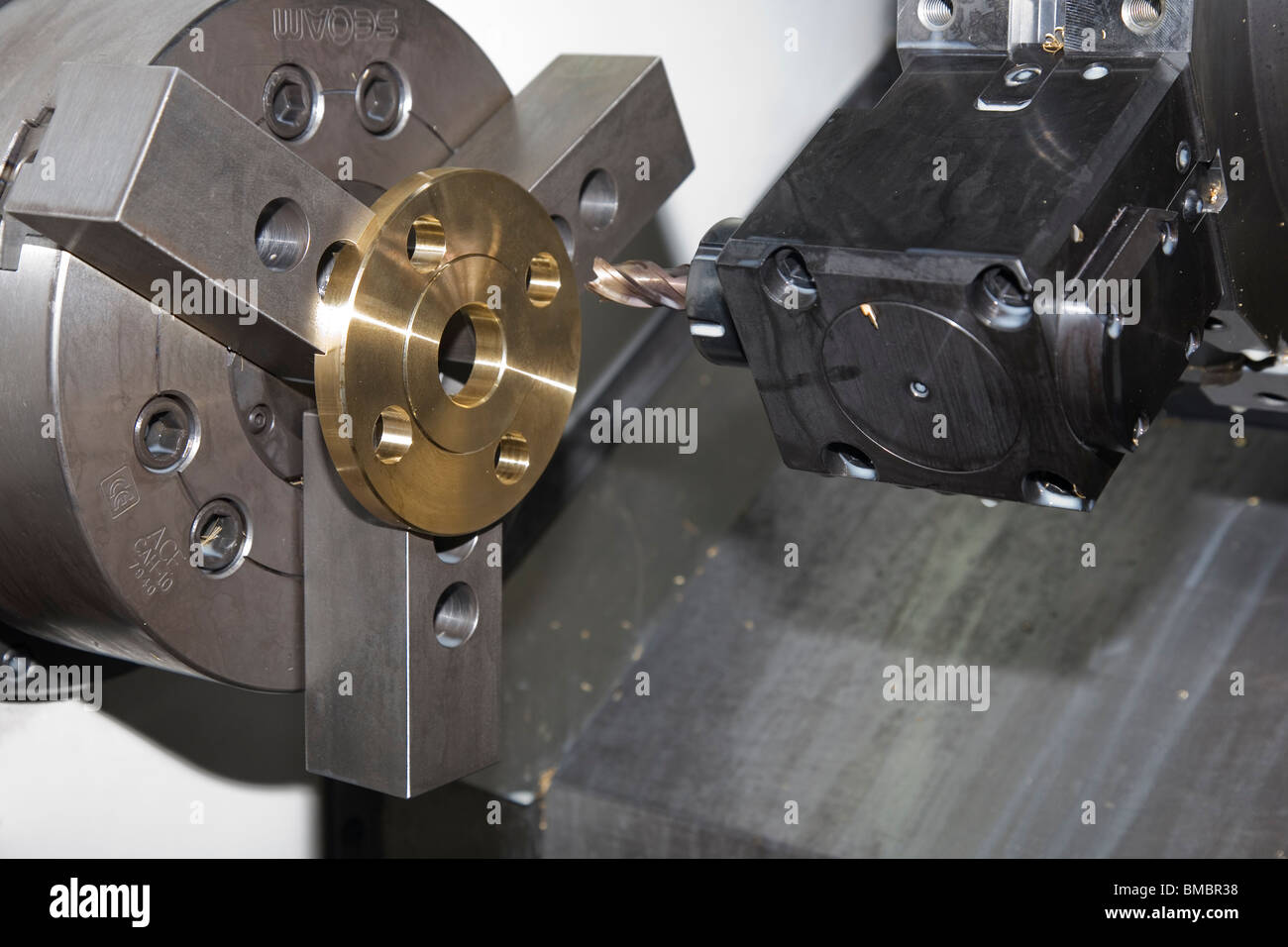 CNC lathe machine with Brass component in jaws of Chuck about to be drilled with live turret drill Stock Photo