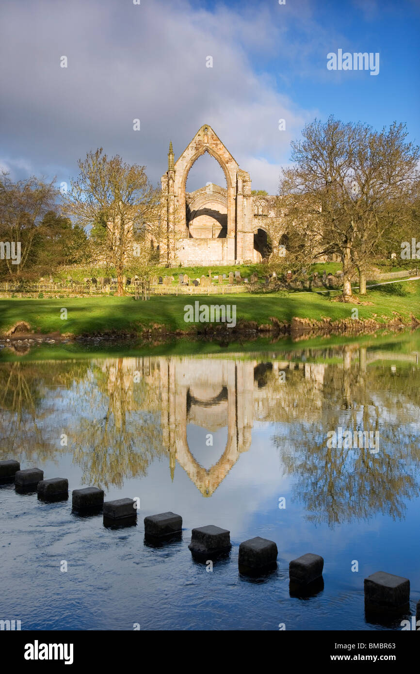View of Bolton Priory, an Augustinian Abbey with stepping stones crossing The River Wharfe, near Skipton, Yorkshire Dales, UK Stock Photo