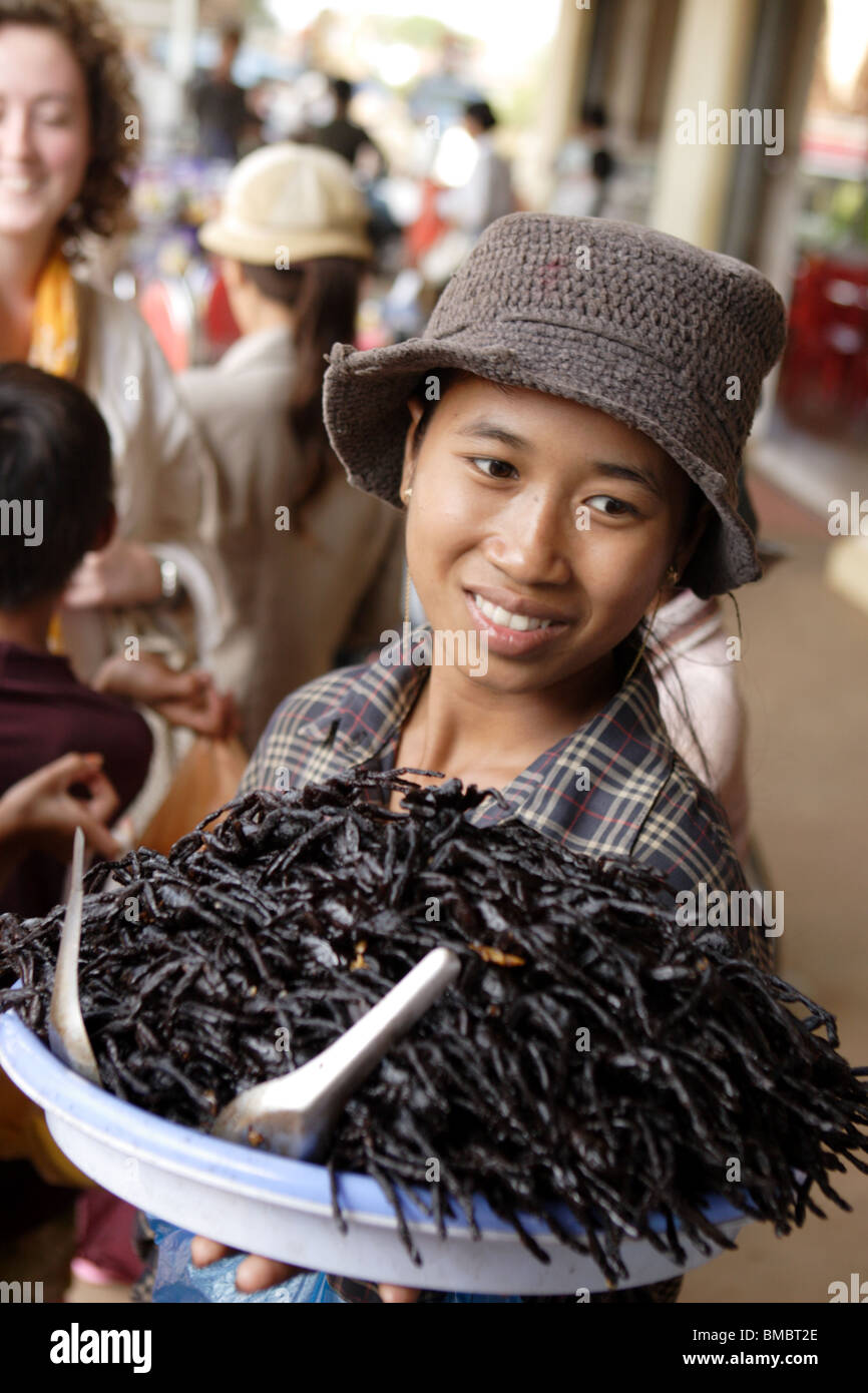 Woman carrying a plate of fried spider, Skuon village Cambodia. Known as Spiderville. Stock Photo
