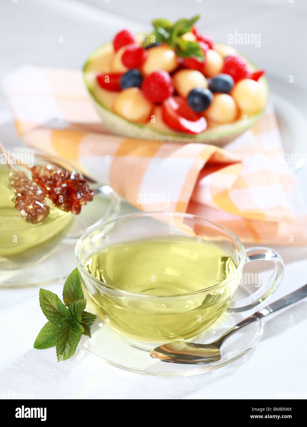 Two cups of green herbal tea with sugar stick and fresh fruits Stock Photo