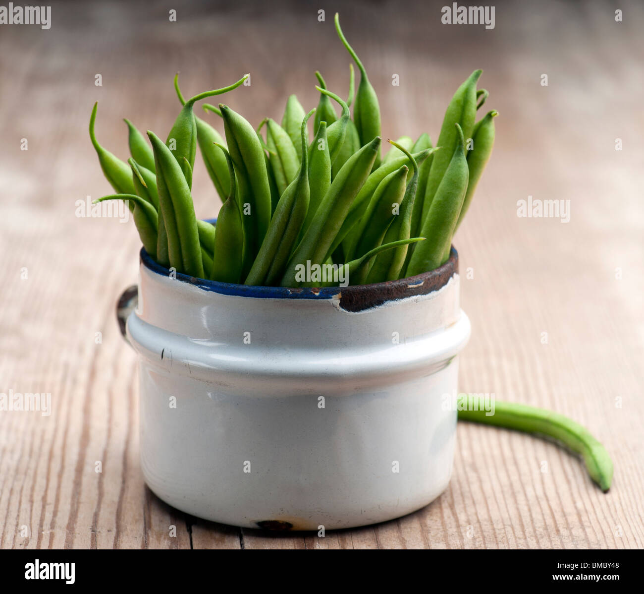 Freshly Picked Green Beans In An Old Enamel Mug On A Wooden Surface Stock Photo