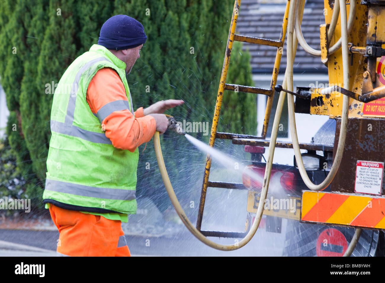 A ready mix concrete driver cleans concrete off his lorry after a