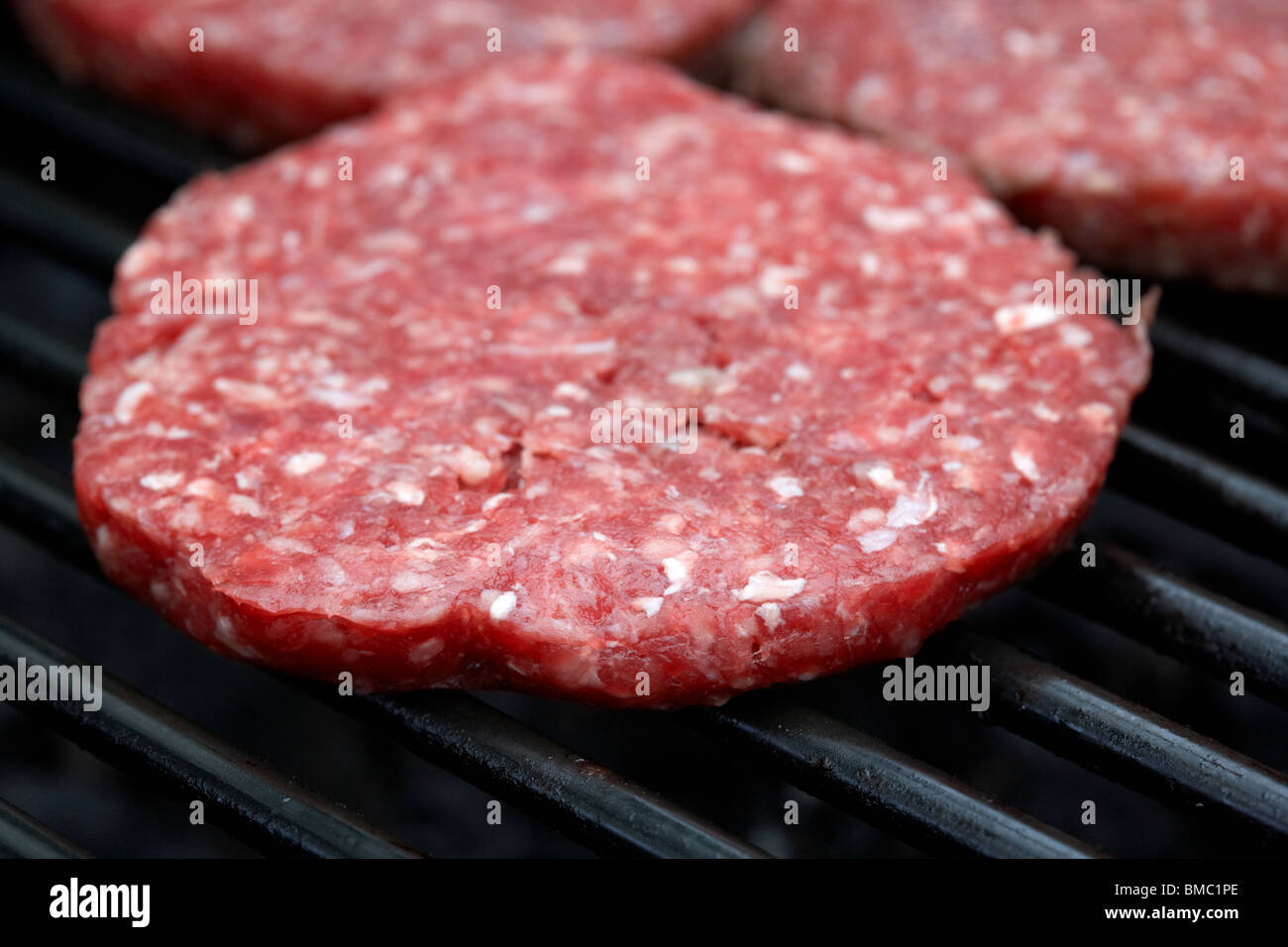 raw steak burgers cooking on a barbeque grill Stock Photo Alamy