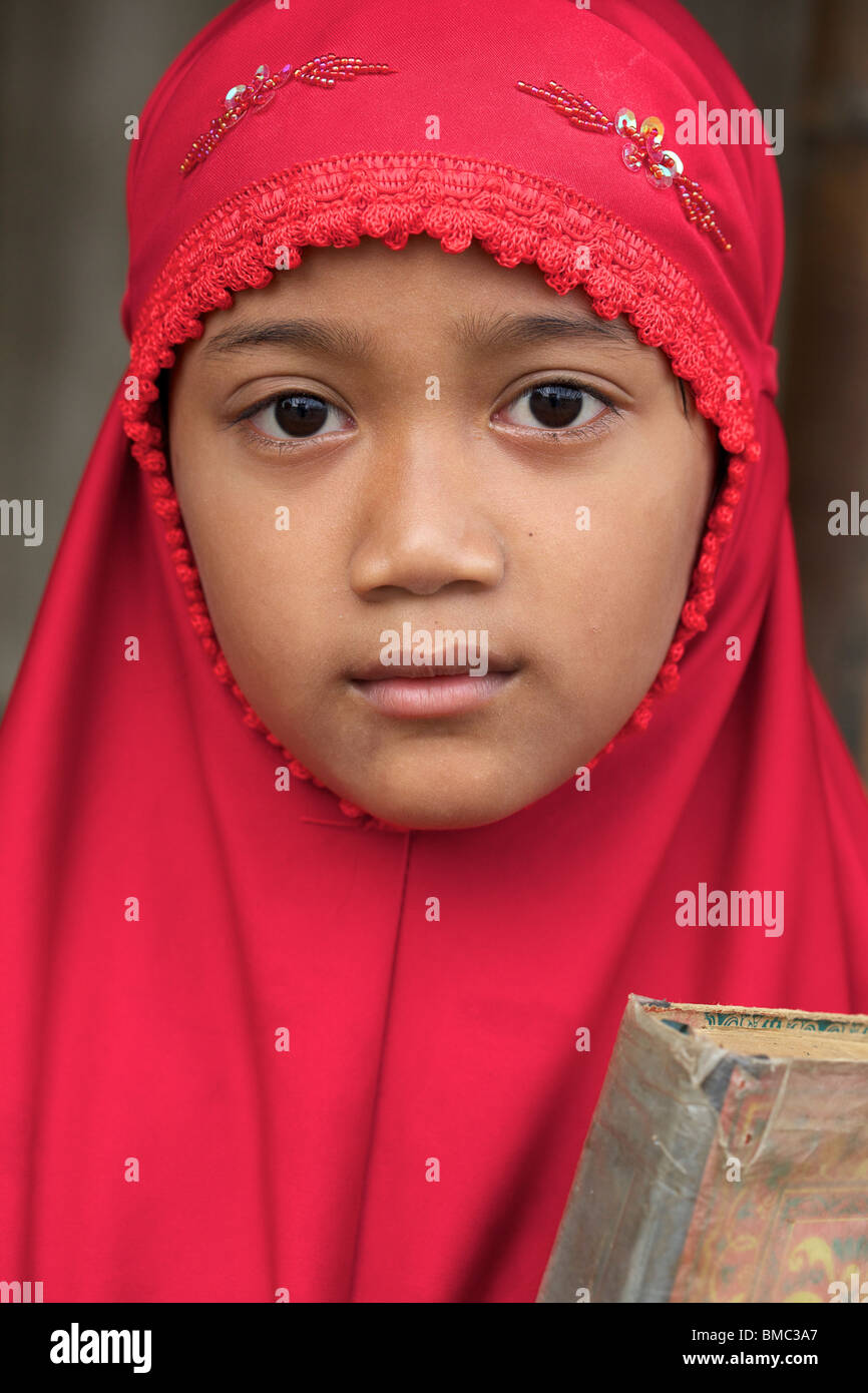 Young muslim girl wearing red veil while holding Quran, East Java, Indonesia Stock Photo