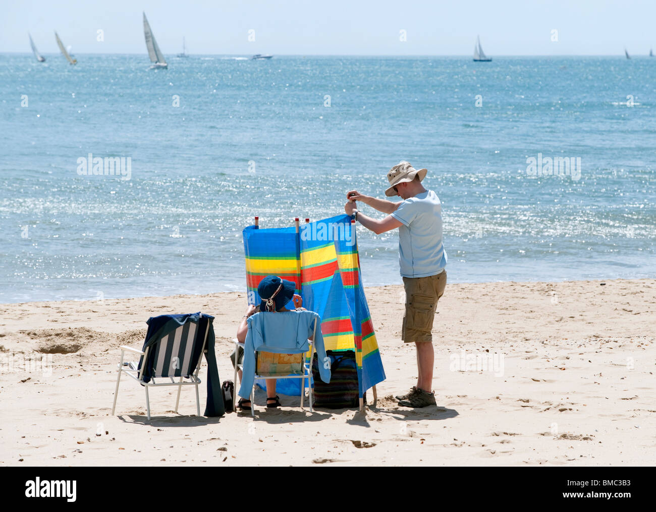Holidaymakers put up windbreakers on the beach at Poole, Dorset Stock Photo