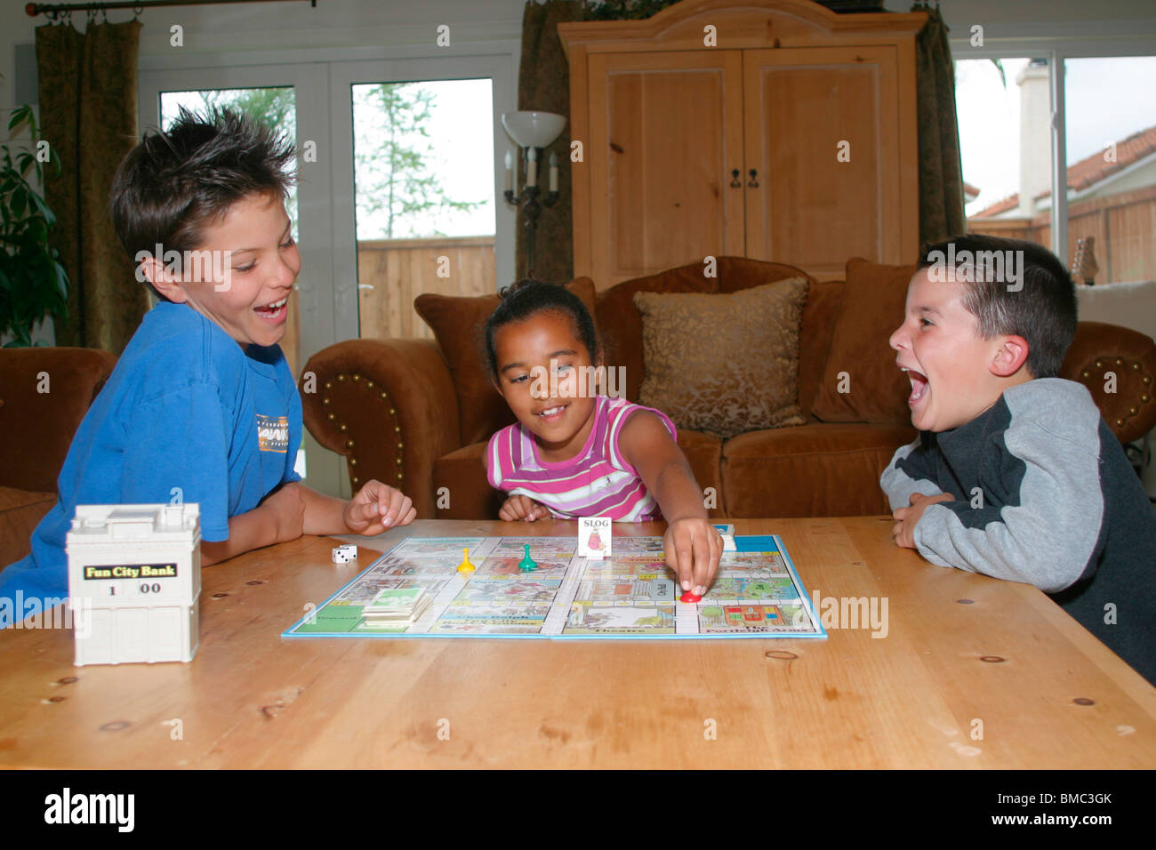 3 Multi Racial Kids Playing Board Game Indoor Inside On Table Level