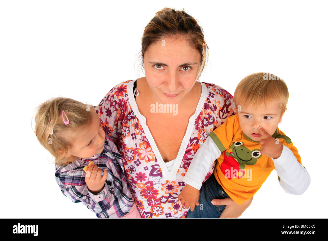 nerved mother with her children on her arms, girl eating a biscuit, boy picking his nose Stock Photo