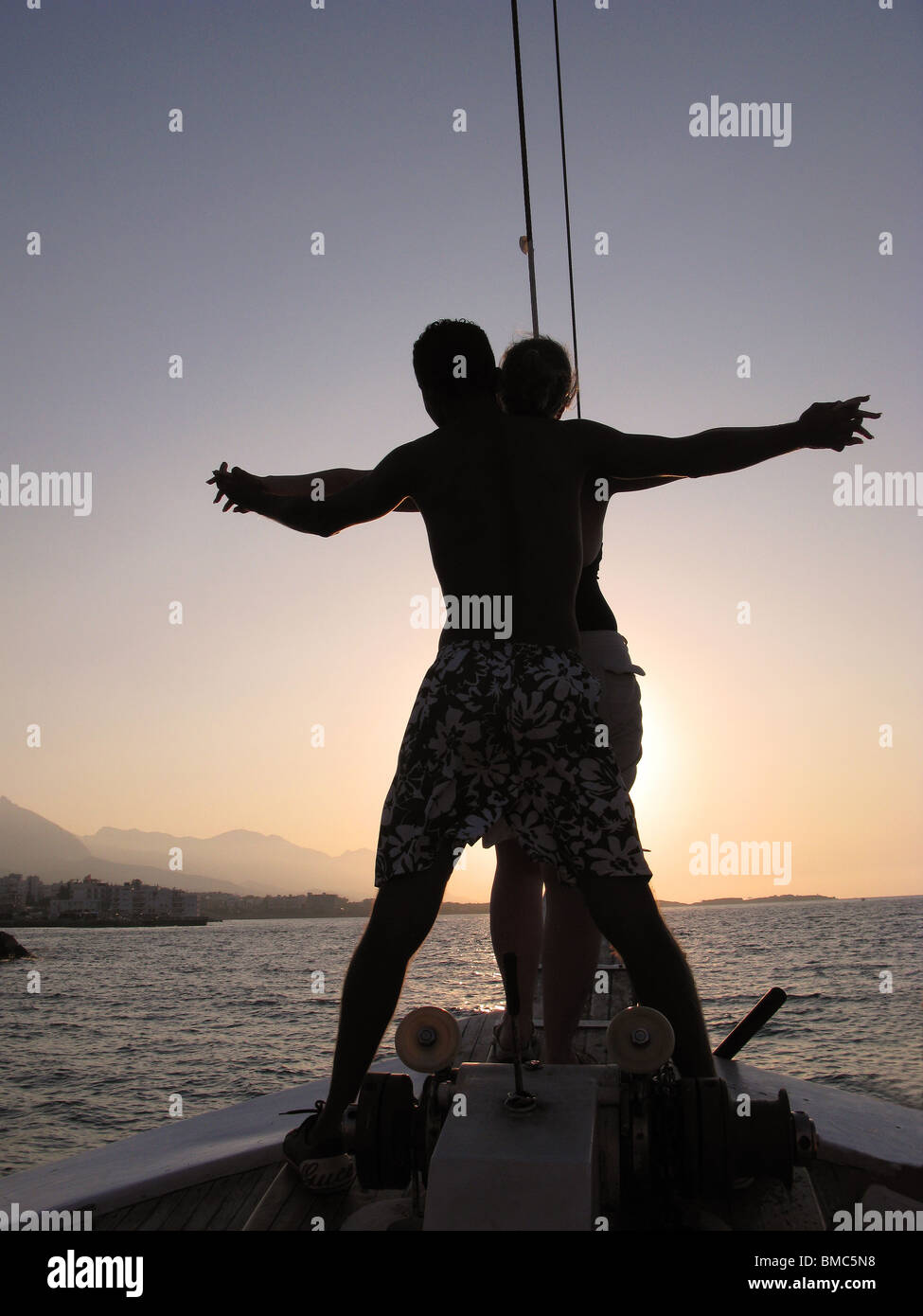 KYRENIA, NORTH CYPRUS. A young couple standing on the prow of a Turkish gulet and sailing into the sunset. Stock Photo