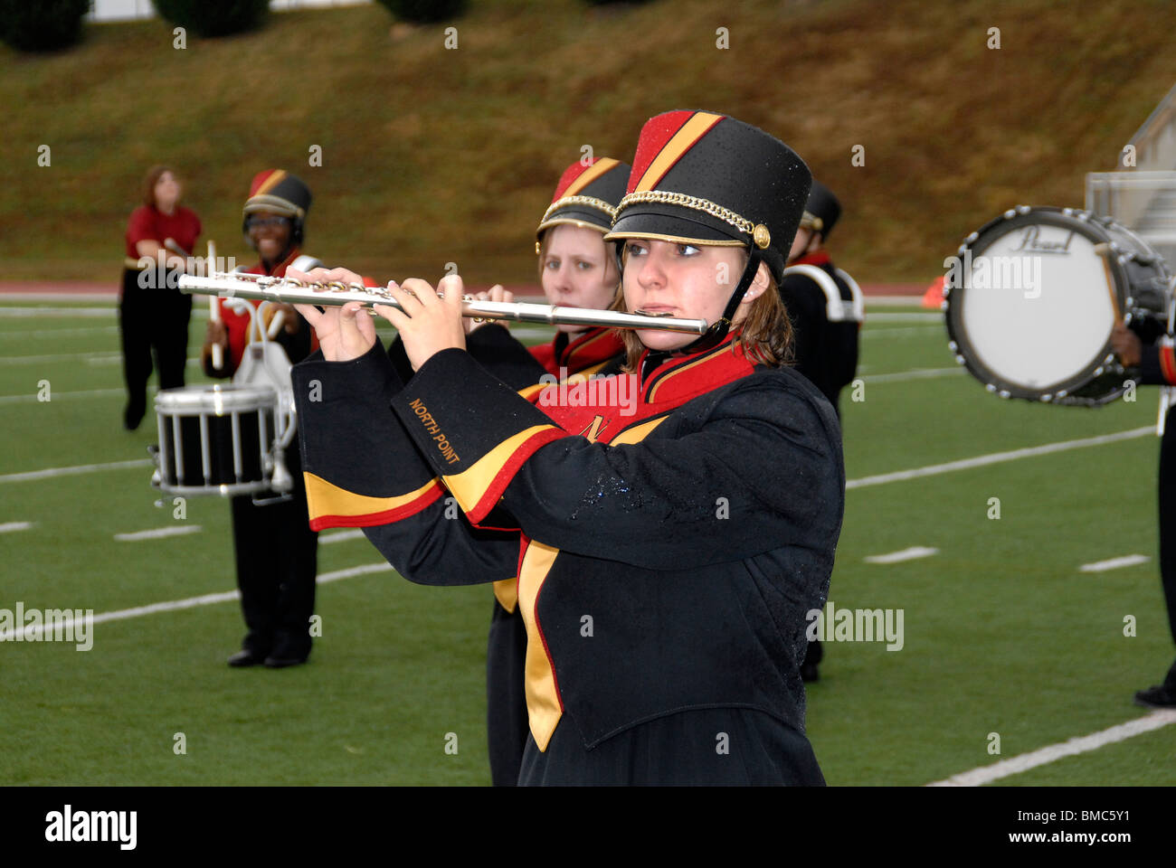 member of a high school marching band playing a flute during a half time show at a high school football game Stock Photo