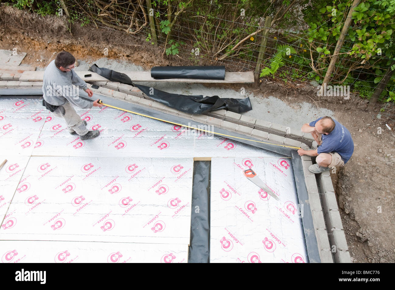 Builders lay under floor insulation into a house extension in Ambleside, UK. Stock Photo