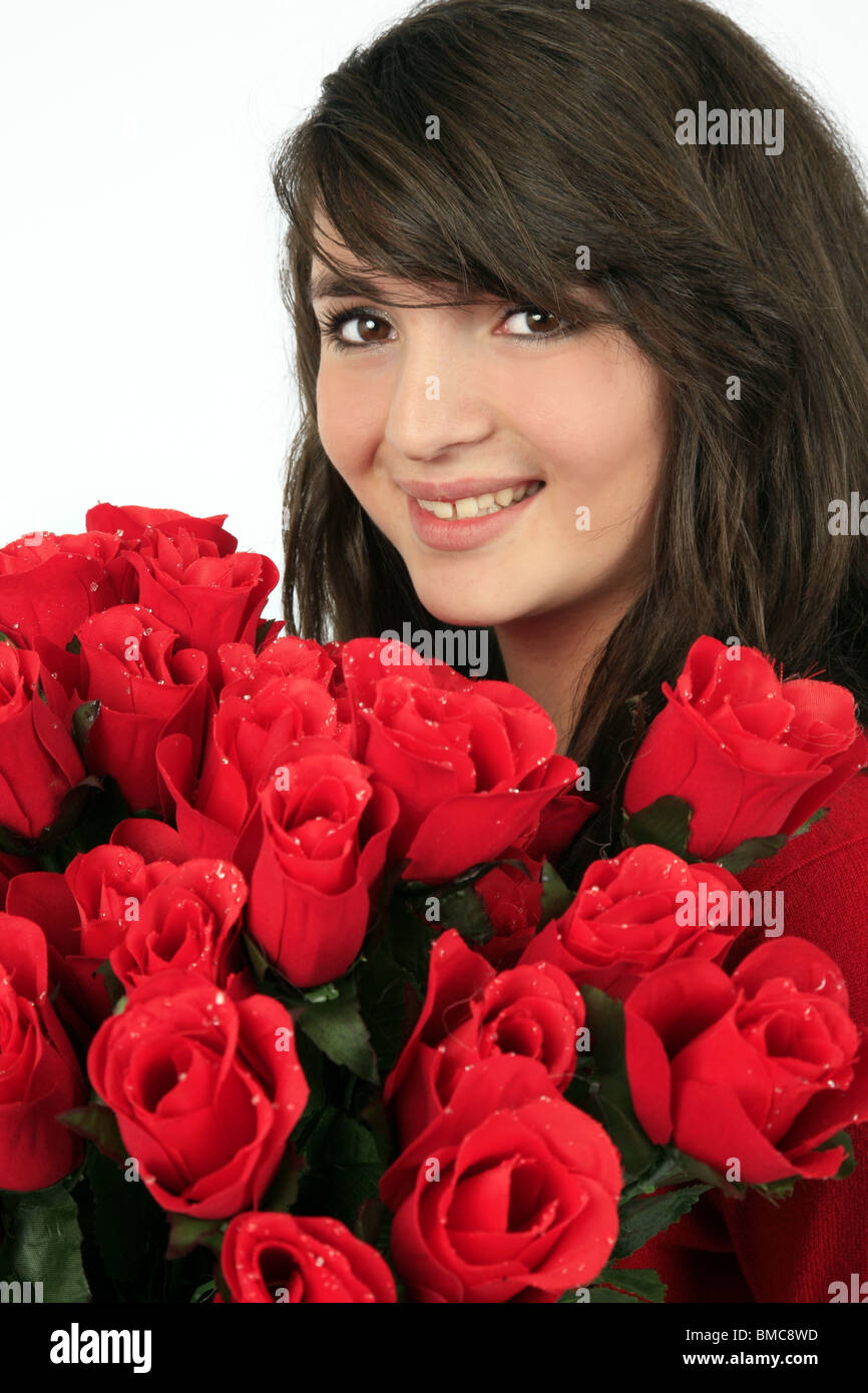 girl hiding behind a bunch of red roses Stock Photo