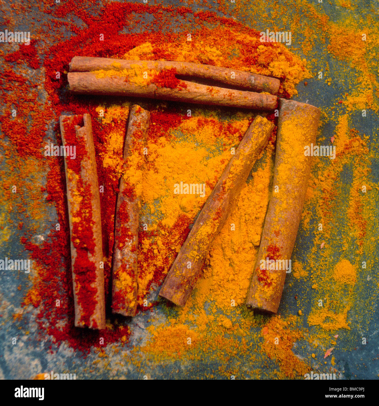 Colorful spices and cinnamon sticks arranged artistically on a textured surface showcasing vibrant hues and natural elements Stock Photo
