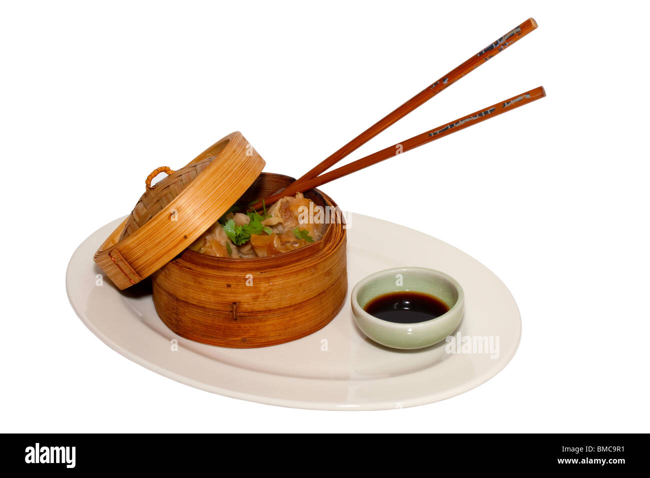 Dim Sum with chopsticks in bamboo serving dish cut out on white background and surface Stock Photo