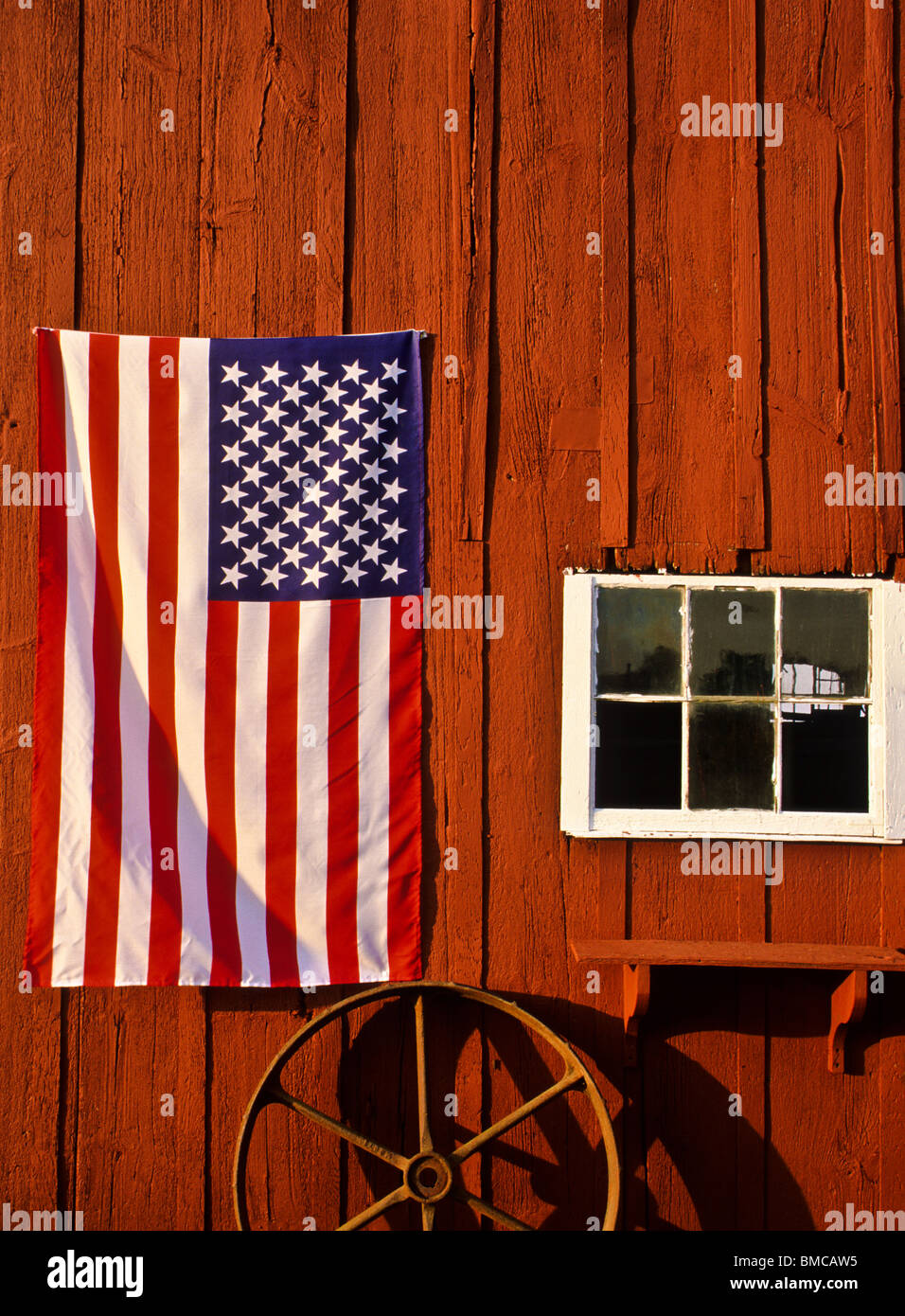 Close up American flag vertical close up on a vintage red barn with a wagon wheel and window, Middlesex County, New Jersey farm, US FS17.69MB 300ppi Stock Photo