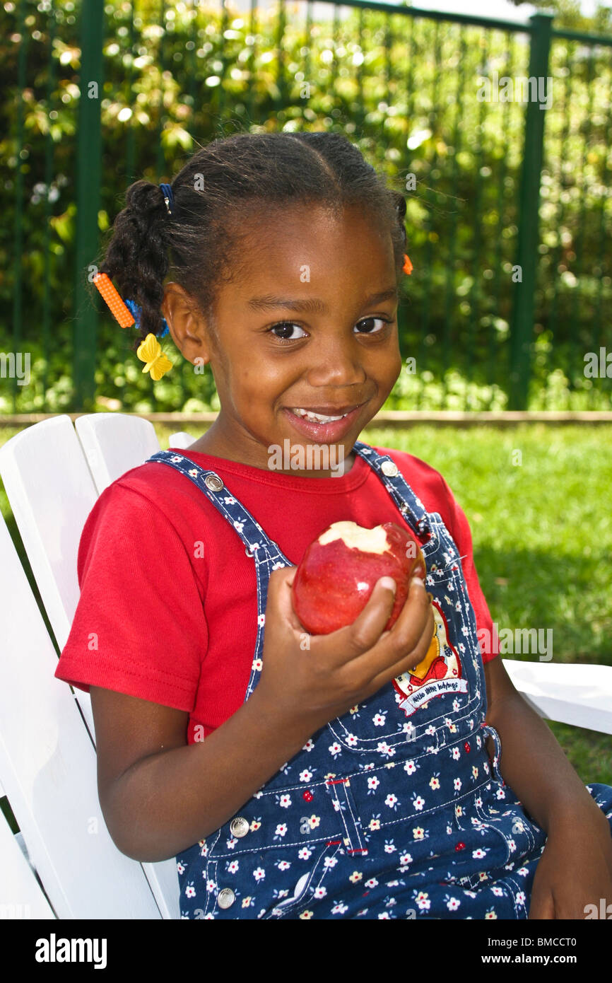 4-5 year years old African American girl eating big red apple eye contact MR  © Myrleen Pearson Stock Photo