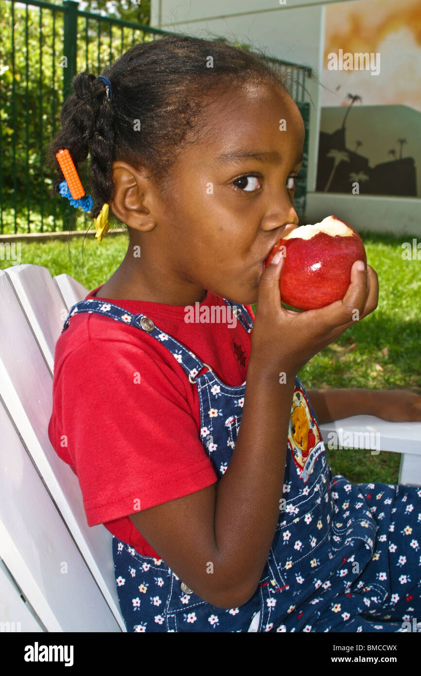 4-5 year years old African American girl eating big red apple. Eye contact MR  © Myrleen Pearson Stock Photo