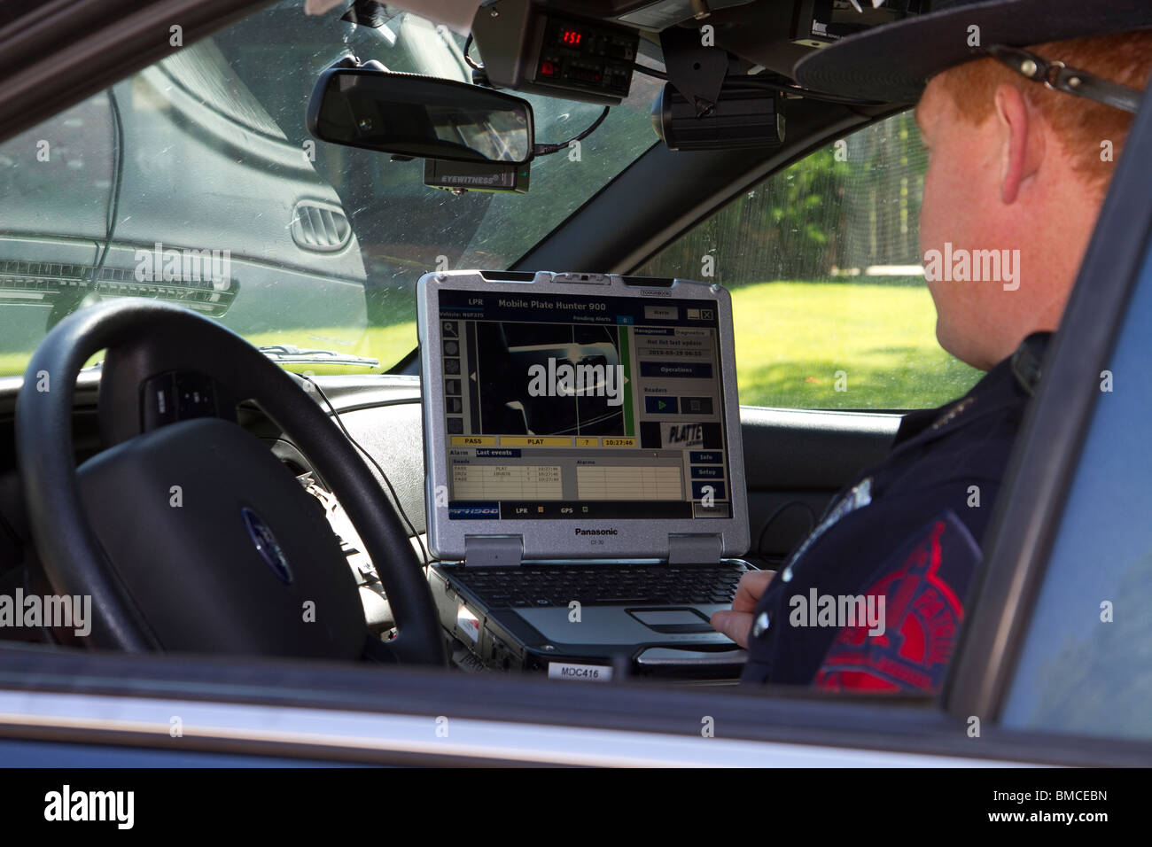 Nebraska State Trooper using laptop computer in cruiser to read output from an Automated License Plate Reader, LPR. Stock Photo